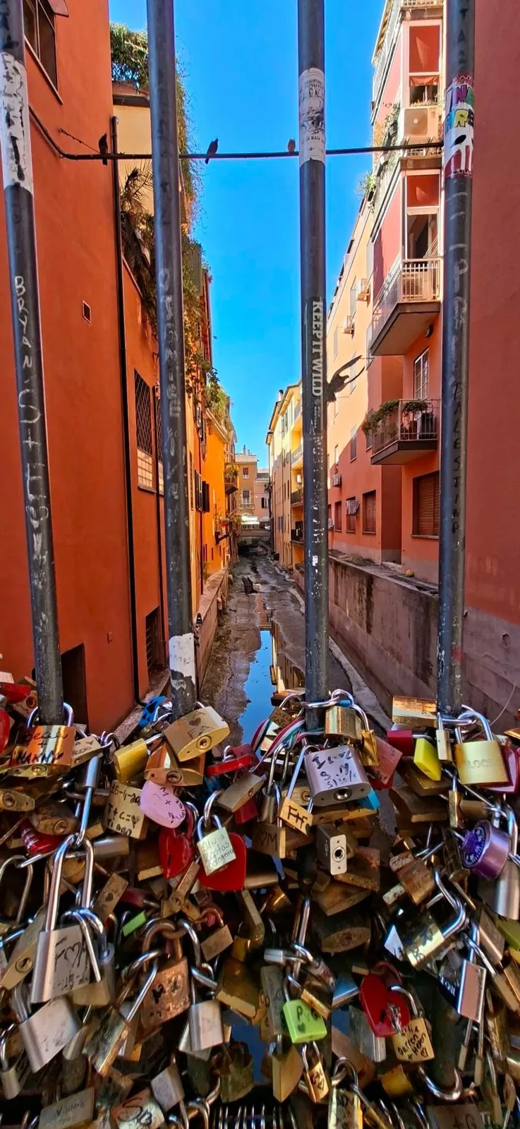 The Moline canal between colourful houses, seen from above a railing covered in padlocks.