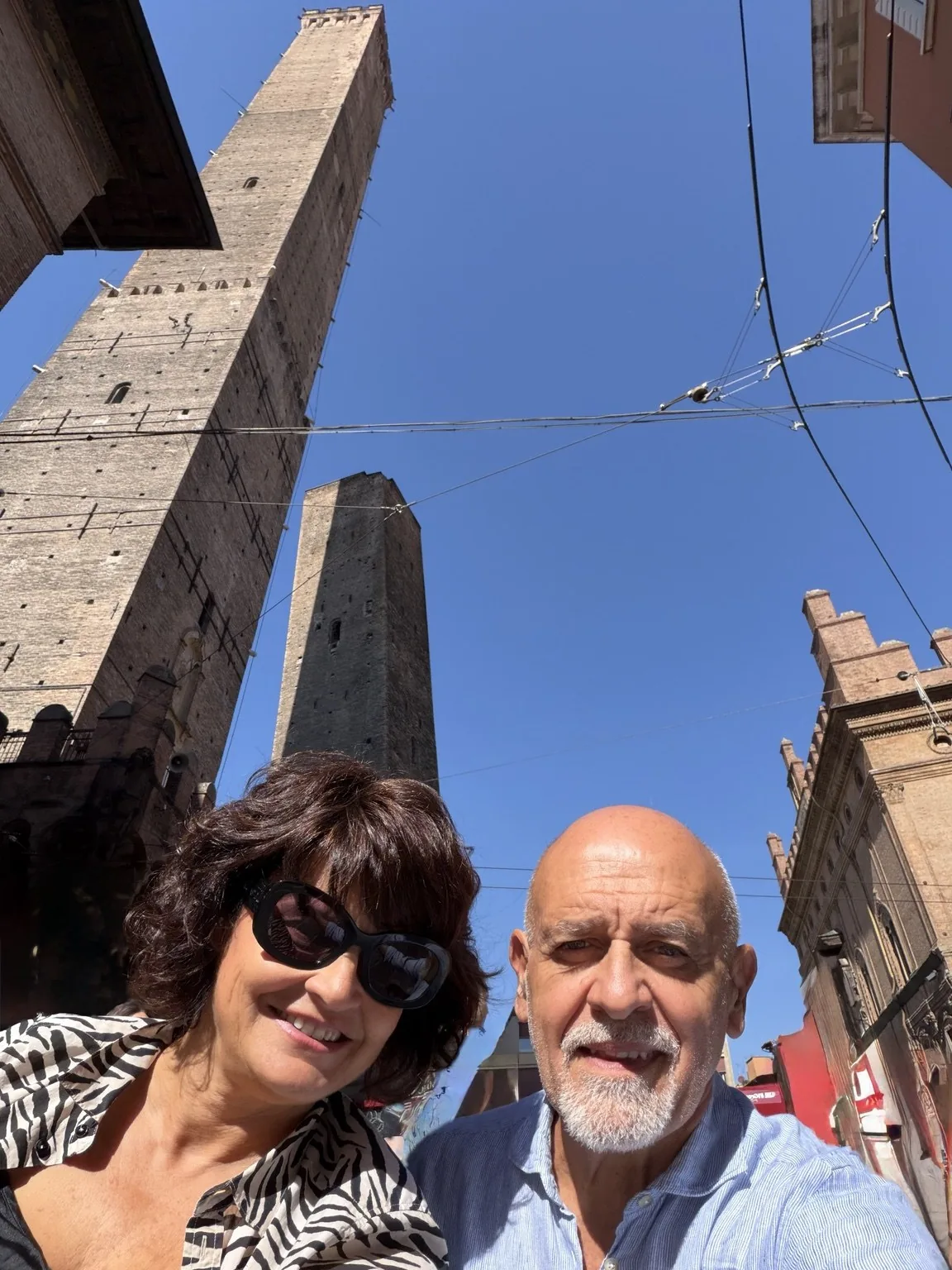 Anna and her companion in a smiling selfie, with the Two Towers behind them.