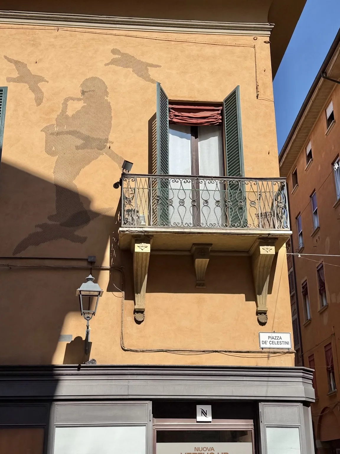 The silhouette of Lucio Dalla with his saxophone, like a shadow on a house front next to a balcony.