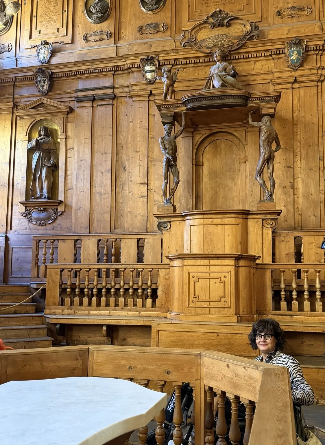 Anna in the Anatomical Theatre, among the wood-panelled walls, the statues and the lecturer’s chair.