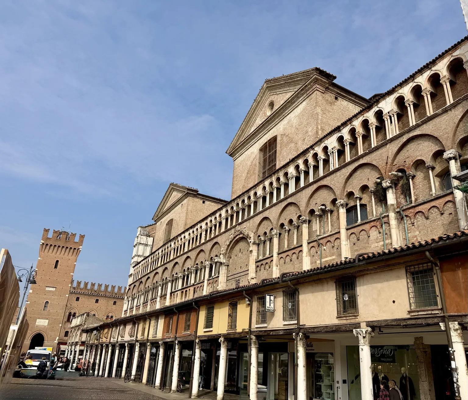 Il fianco della Cattedrale con le file di archetti e, sotto, il porticato con le botteghe della Loggia dei Merciai; in fondo una torre merlata.