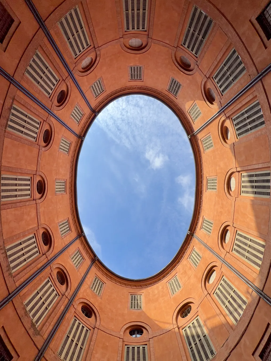 Il cielo azzurro con qualche nuvola, incorniciato dall’apertura ovale della Rotonda Foschini vista dal basso.
