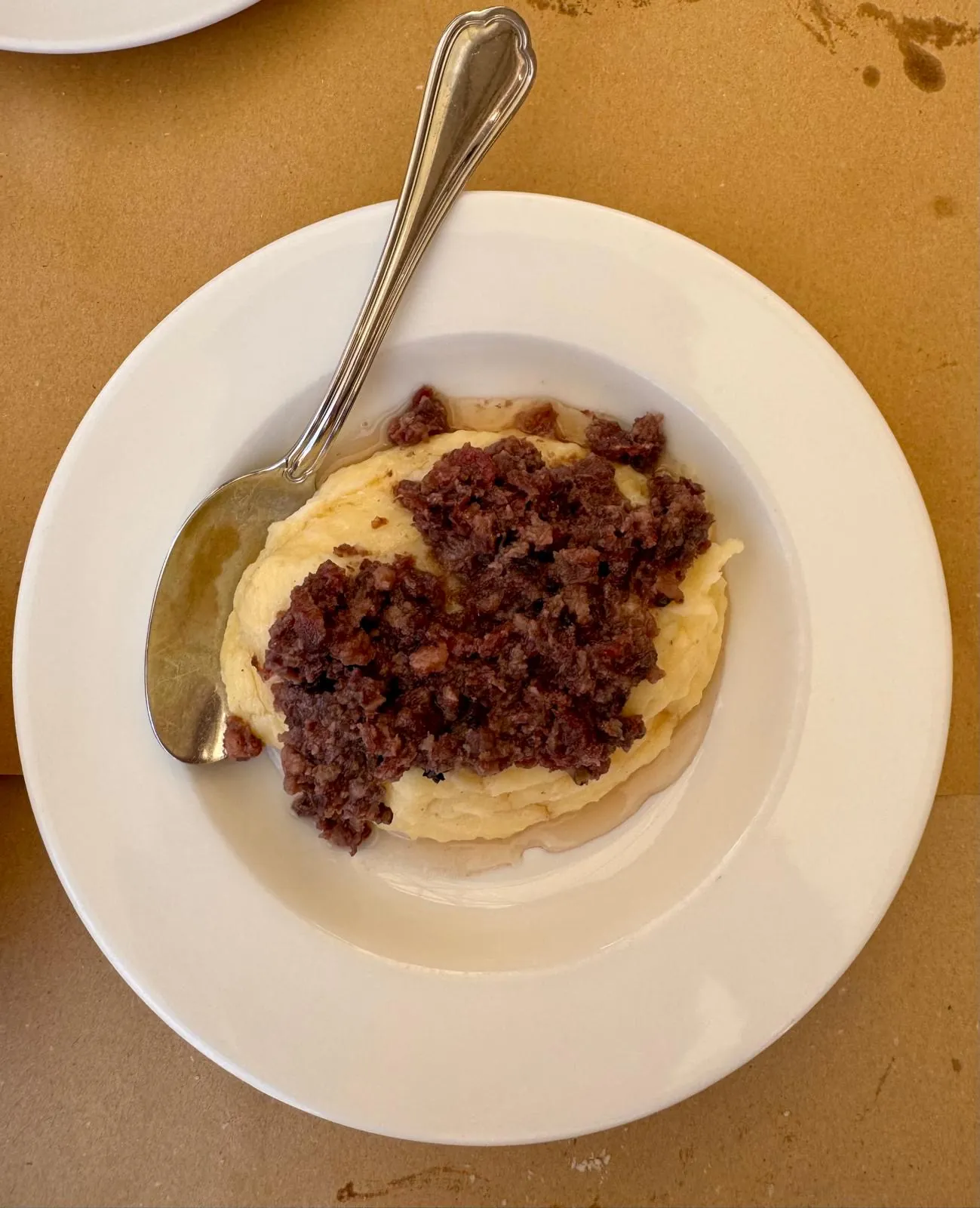 Un piatto bianco con il purè di patate e, sopra, la salamina da sugo sbriciolata.