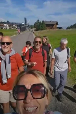 Selfie of the group of friends walking along a road through the alpine meadows.