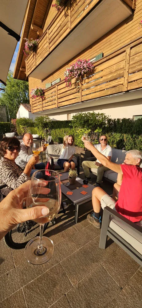 Friends sitting on the terrace raise their glasses for a toast.