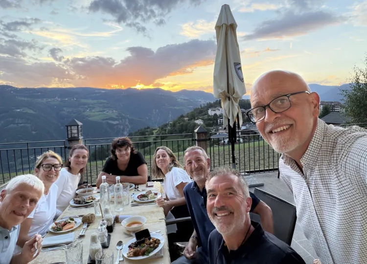 Group selfie at dinner on the terrace, with the sunset sky in the background.