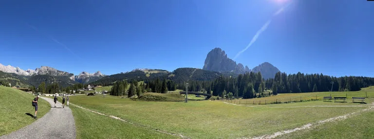 Panorama of a path through the meadows, with the Sassolungo towering in the background.