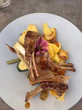 A plate of lamb chops with potatoes and vegetables, decorated with a flower.