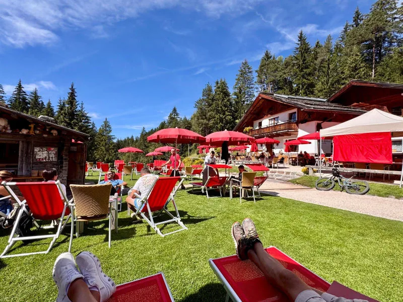 Red deckchairs and parasols on the lawn in front of the restaurant, seen from a sun lounger.