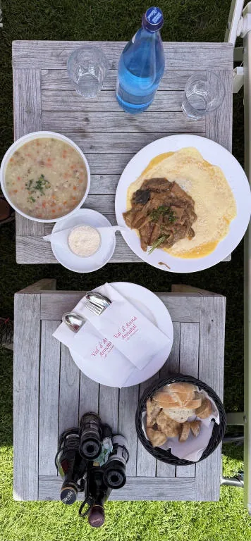 Two low wooden tables seen from above, with lunch plates, water and bread.