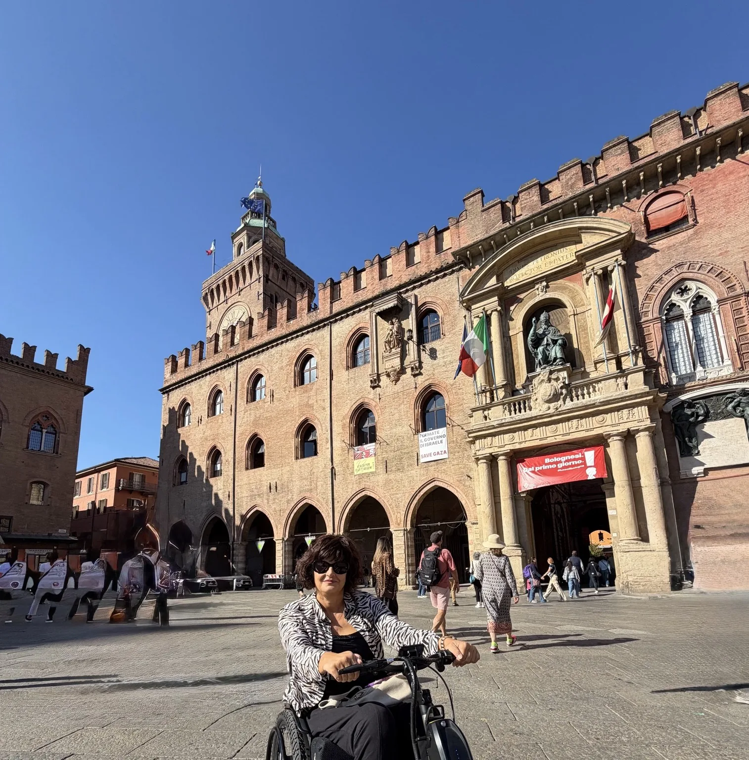 Anna sorridente sul suo Triride in Piazza Maggiore a Bologna, davanti a Palazzo d’Accursio.