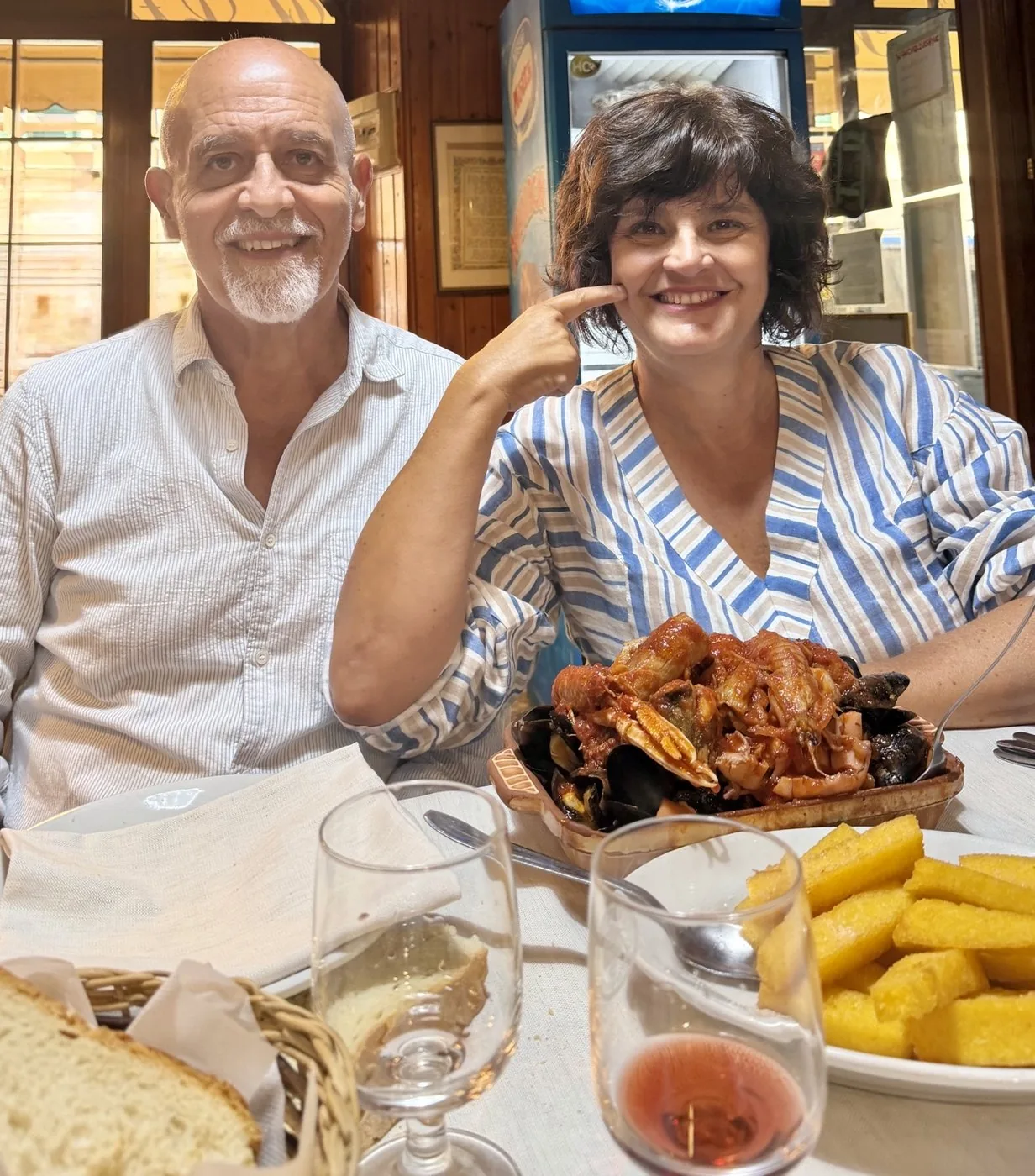 Anna and her companion smiling at the table, in front of the cacciucco and a plate of scagliozzi.