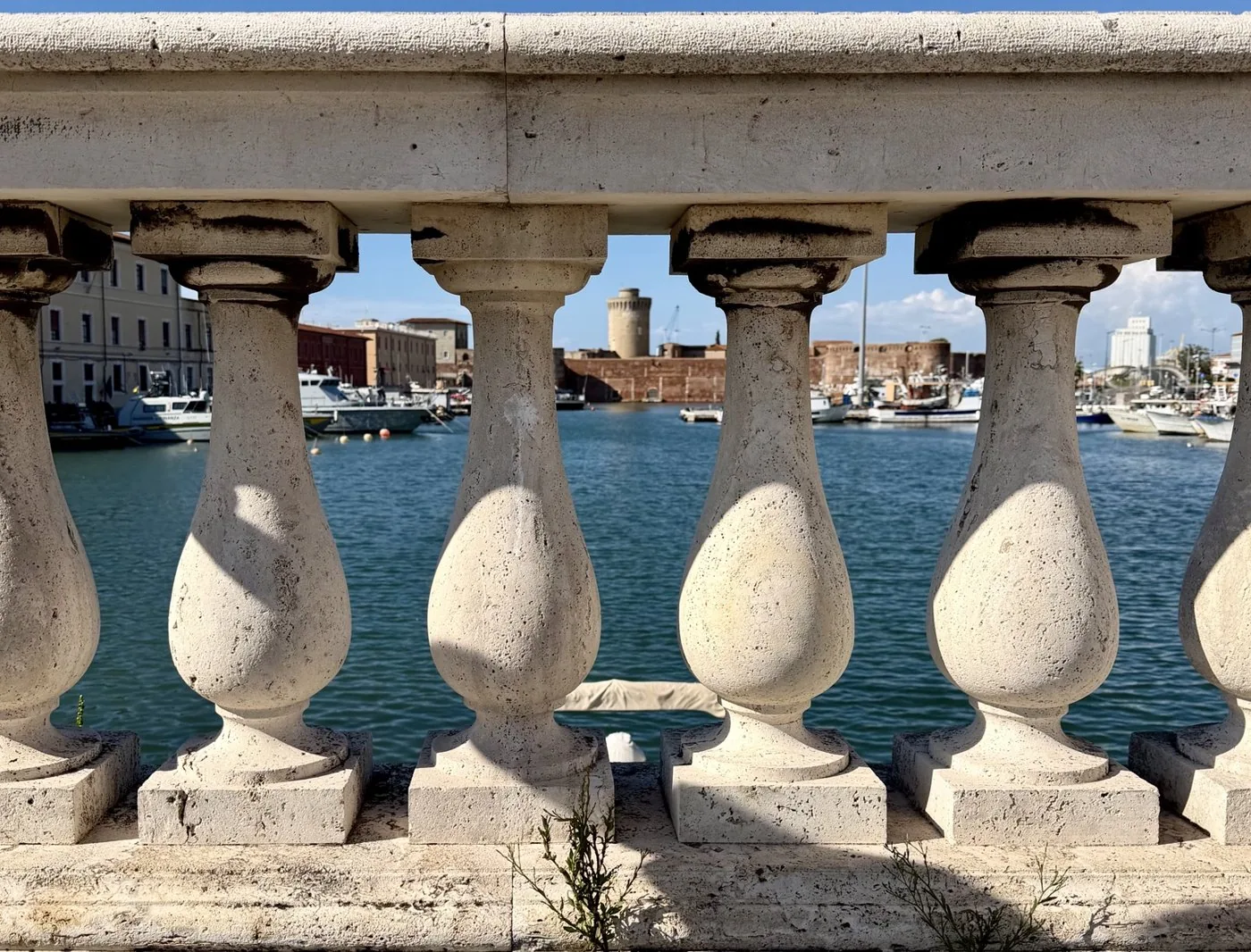 The harbour and a tower seen through the columns of a stone balustrade.