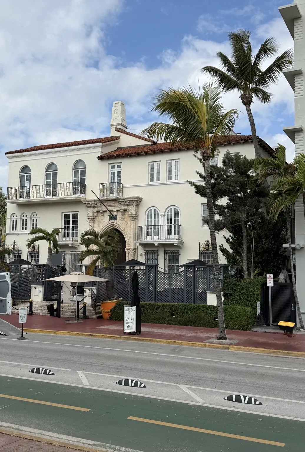 The pale, Mediterranean-style Casa Casuarina mansion among the palm trees, seen from across the street.