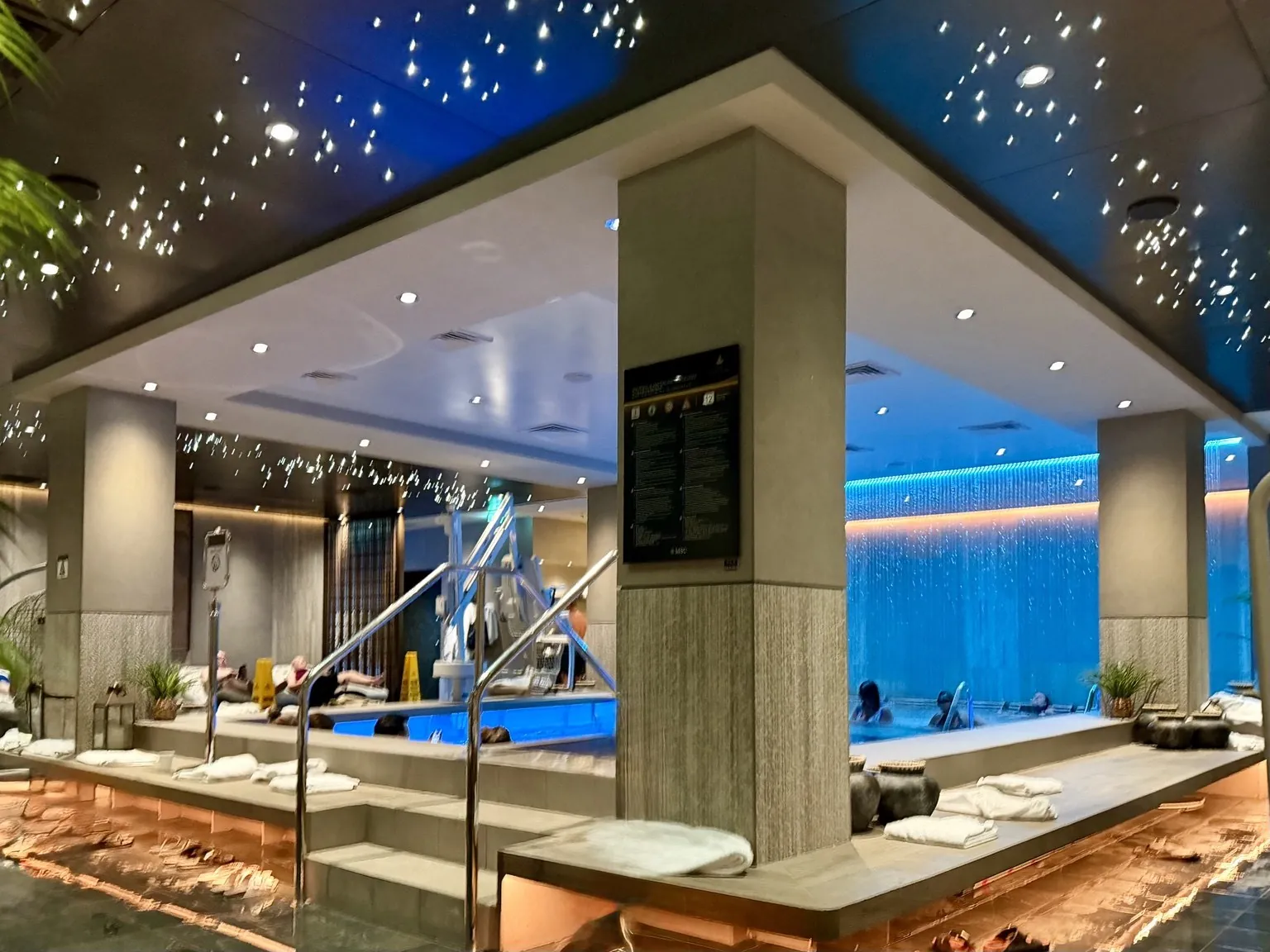 A whirlpool lit in blue beneath a dark ceiling dotted with tiny lights.