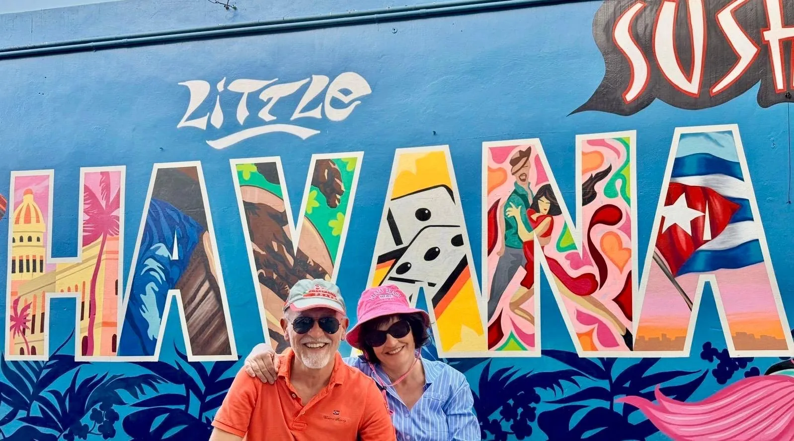 Anna and her companion in front of a large mural with the words “Little Havana” in colourful letters.
