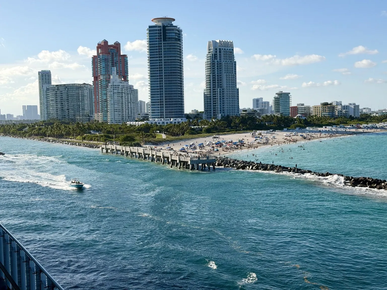 The skyline of Miami Beach’s skyscrapers beyond the channel, with boat wakes on the turquoise water.