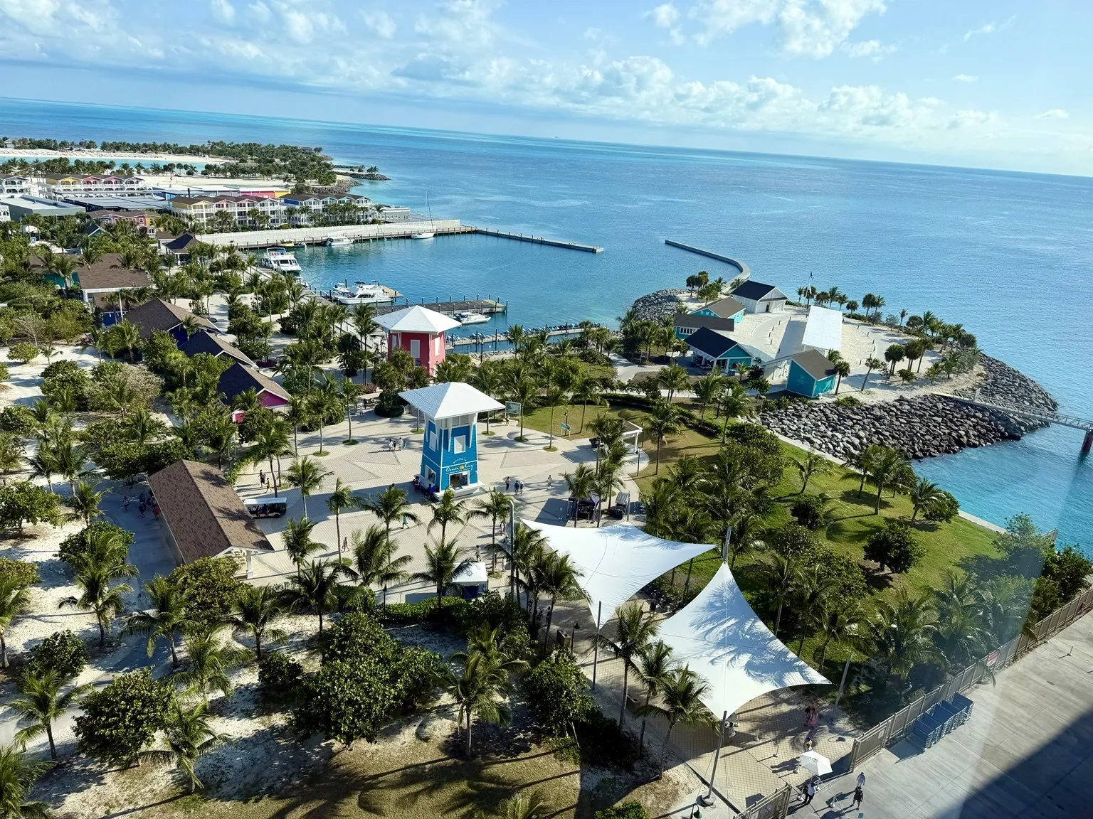 The island seen from high up on the ship: palm trees, paths, white roofs and the turquoise sea all around.