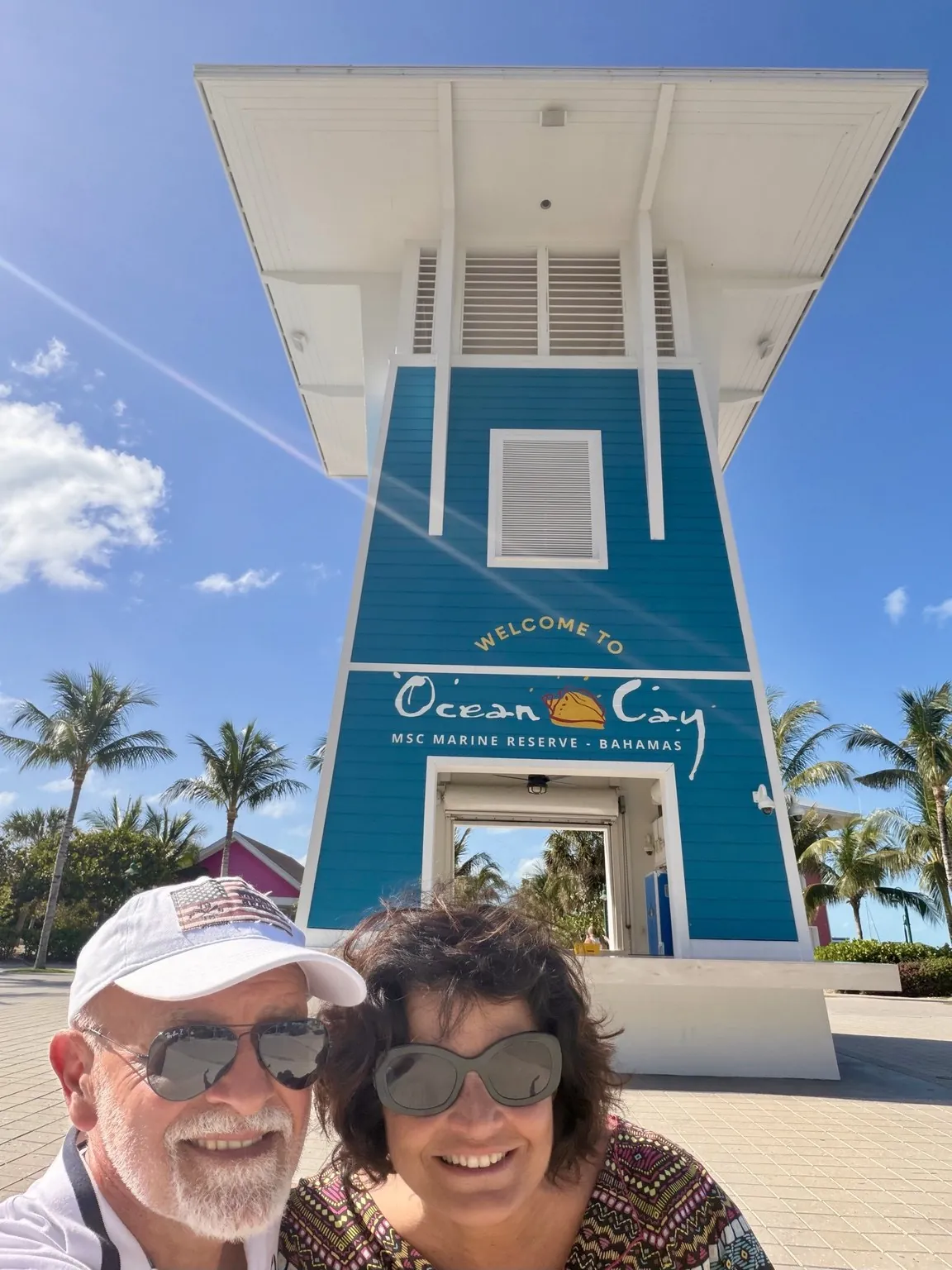 Anna and her companion in a selfie in front of a blue tower with the words “Welcome to Ocean Cay”.