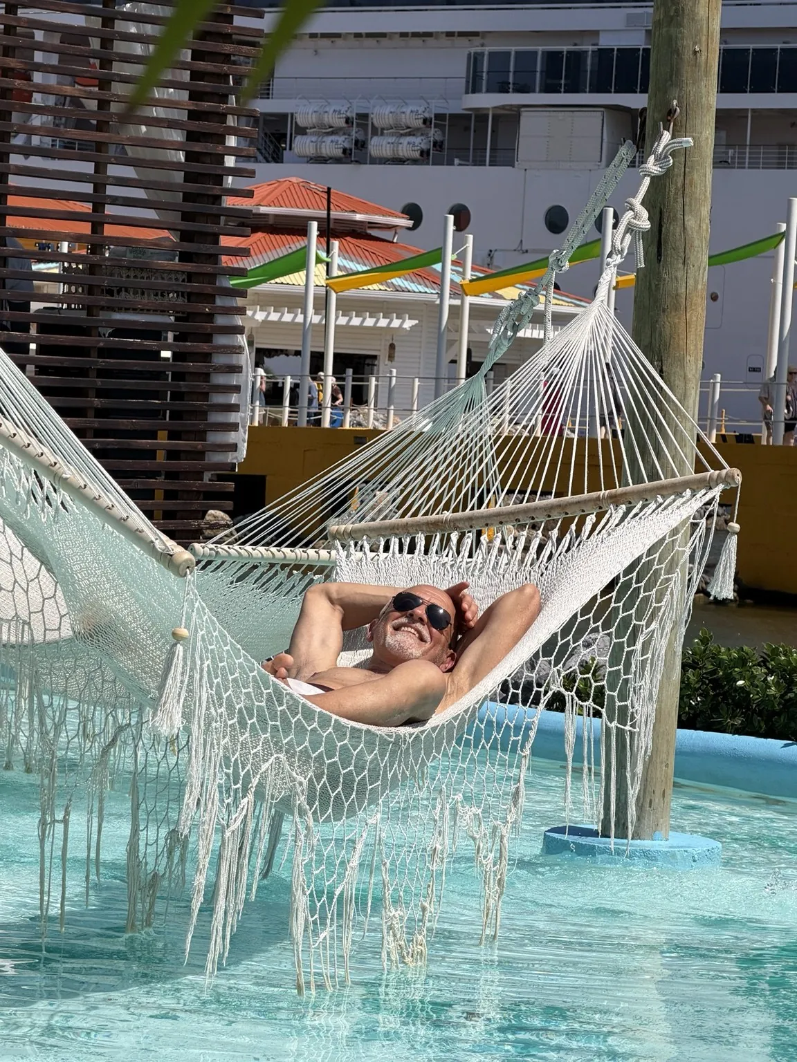 Anna’s companion lying in a white hammock hung above the water of a pool.
