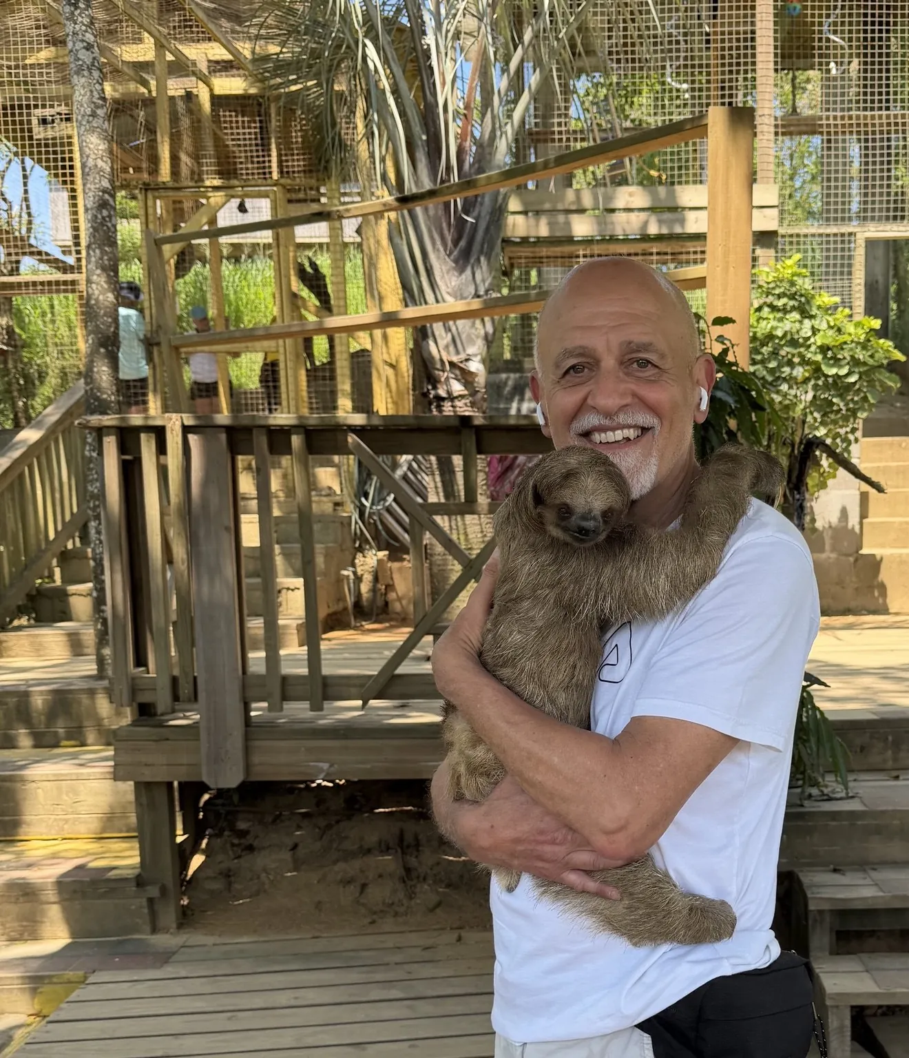 Anna’s companion smiles as he holds a sloth in his arms.