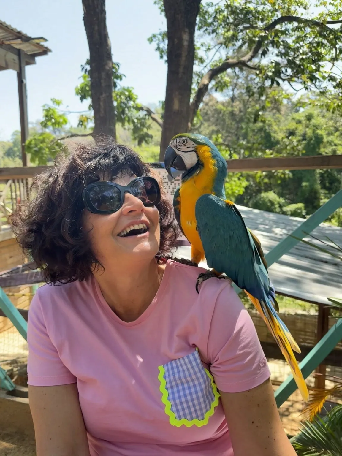 Anna laughs with a blue and yellow parrot perched on her shoulder.