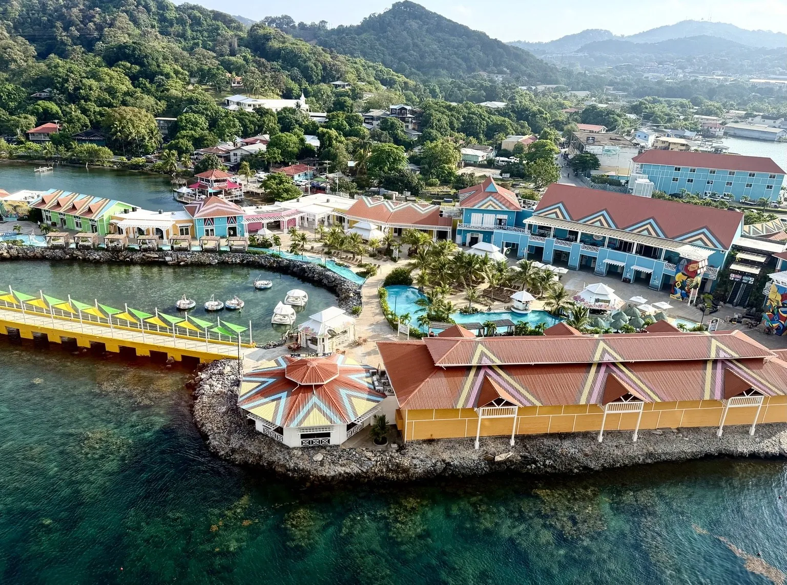 The port seen from above, with colourful-roofed buildings on the water and green hills behind.