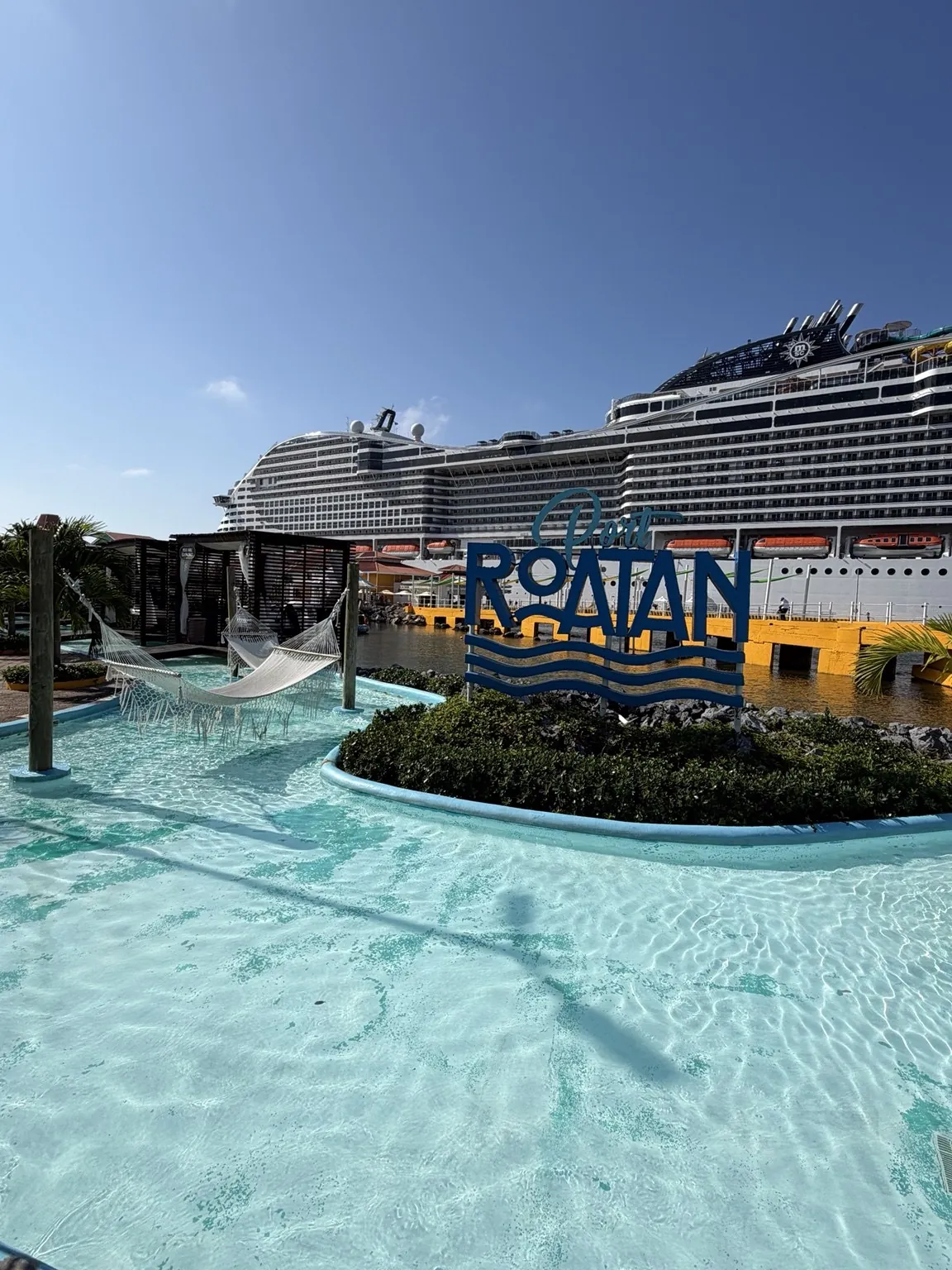 The big “Roatán” sign beside a turquoise pool; in the background, the cruise ship.