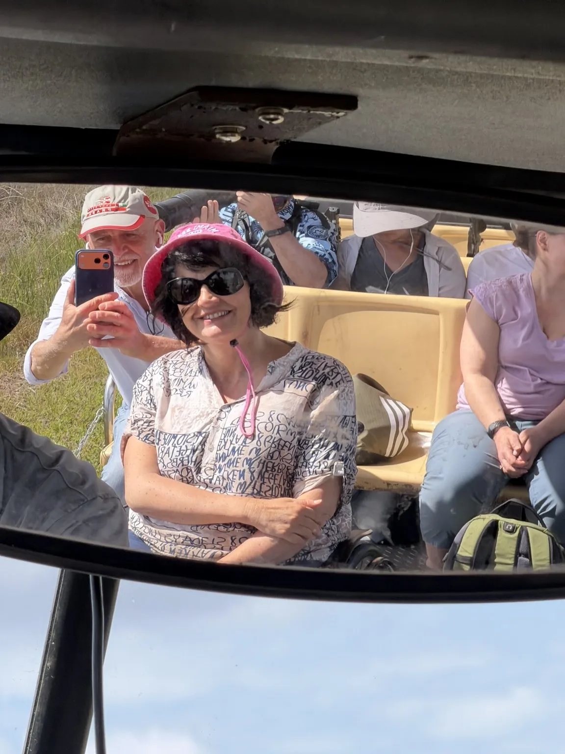 Anna smiling in her pink hat, reflected in the tram’s mirror together with the other passengers.