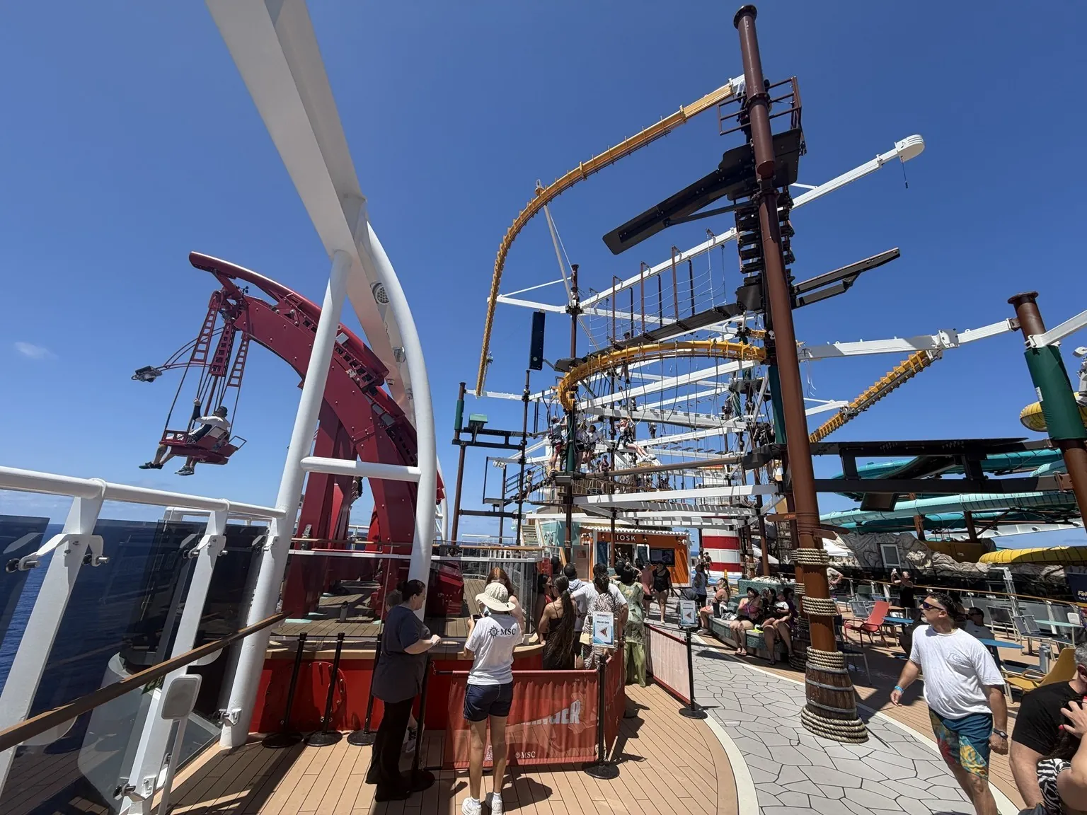 The ropes course with poles, ropes and suspended walkways on the ship’s deck, under a blue sky.