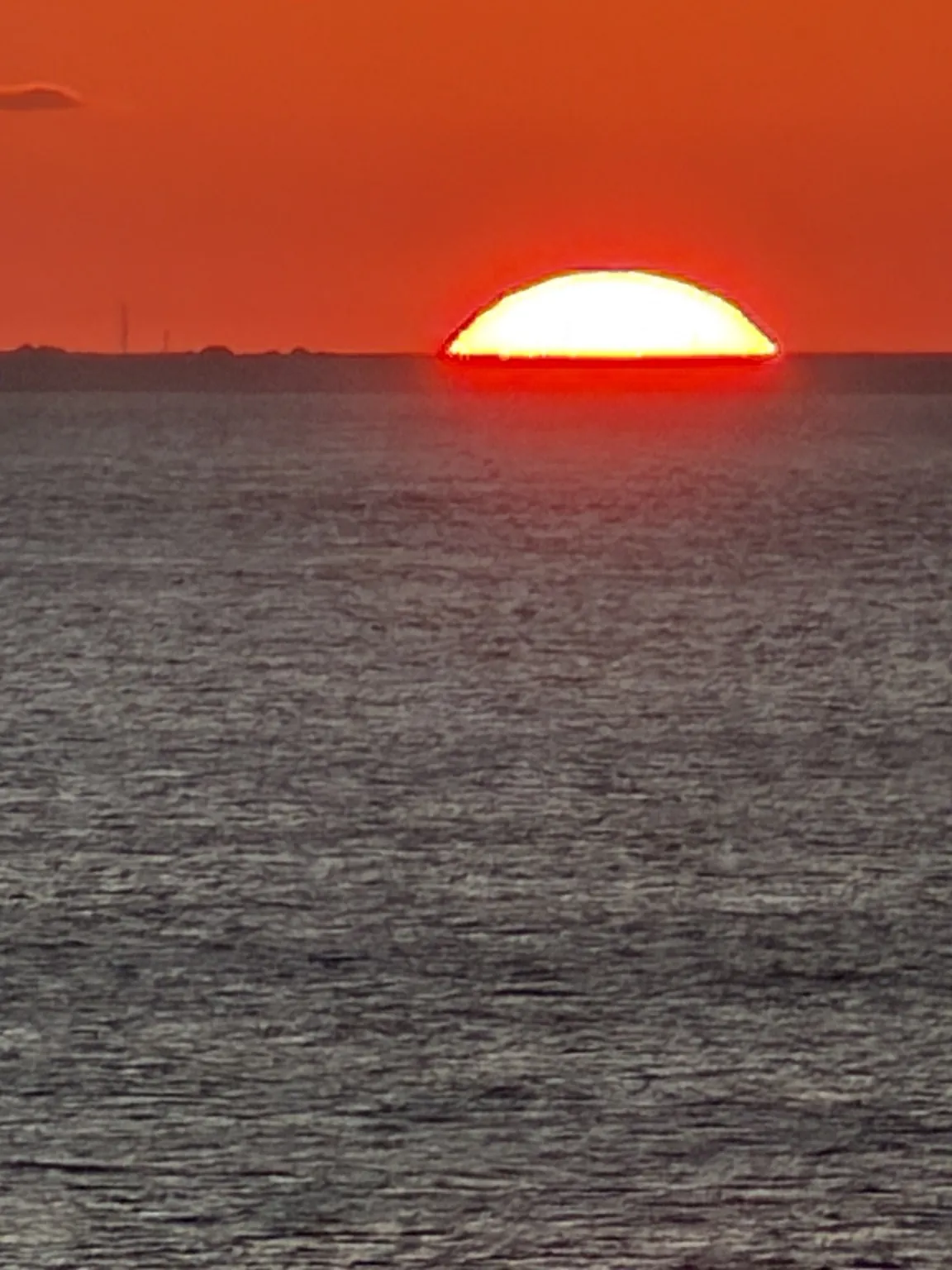 The red sun sinking onto the horizon, above the sea.