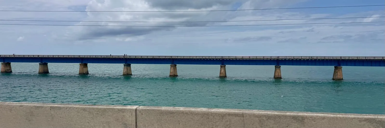 The old bridge on its piers, crossing the turquoise sea from one side of the picture to the other.
