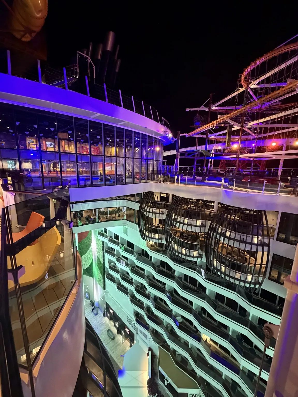 The cabin balconies overlooking the promenade, with green and purple lights in the night.