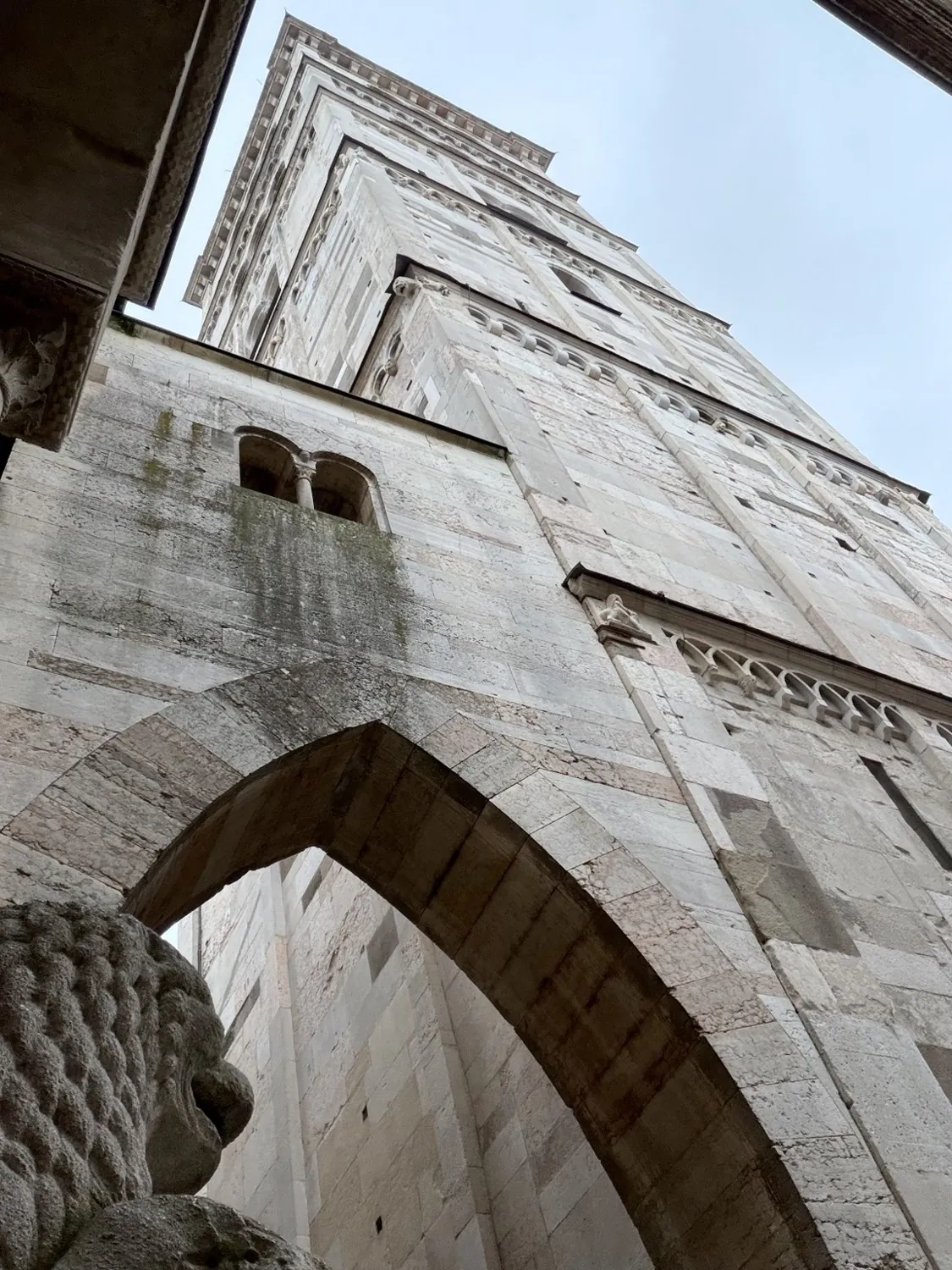 La torre Ghirlandina vista dal basso, attraverso un arco in pietra che la collega al Duomo.