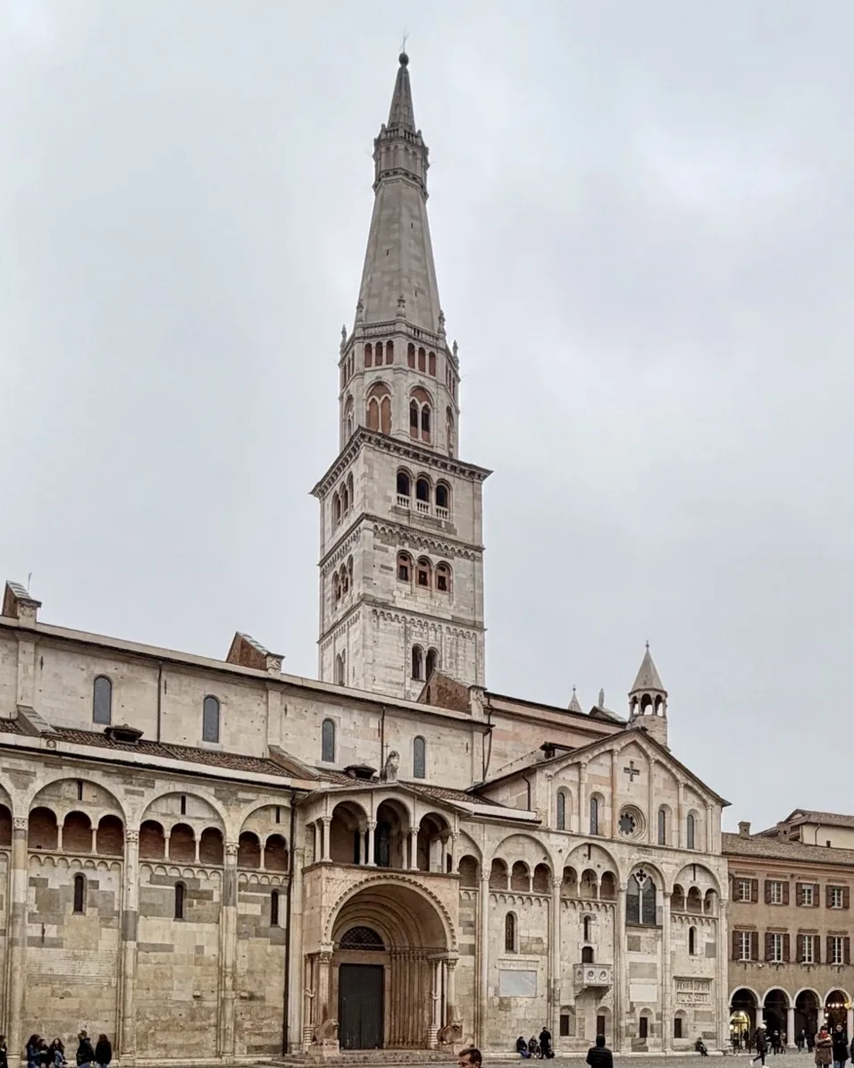 Piazza Grande a Modena sotto un cielo grigio: la torre Ghirlandina e la facciata romanica del Duomo.